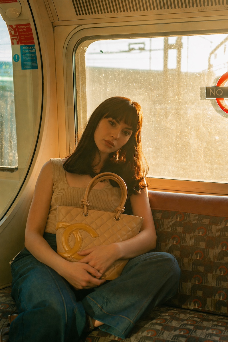 A woman holding a quilted designer tote on a sunlit train